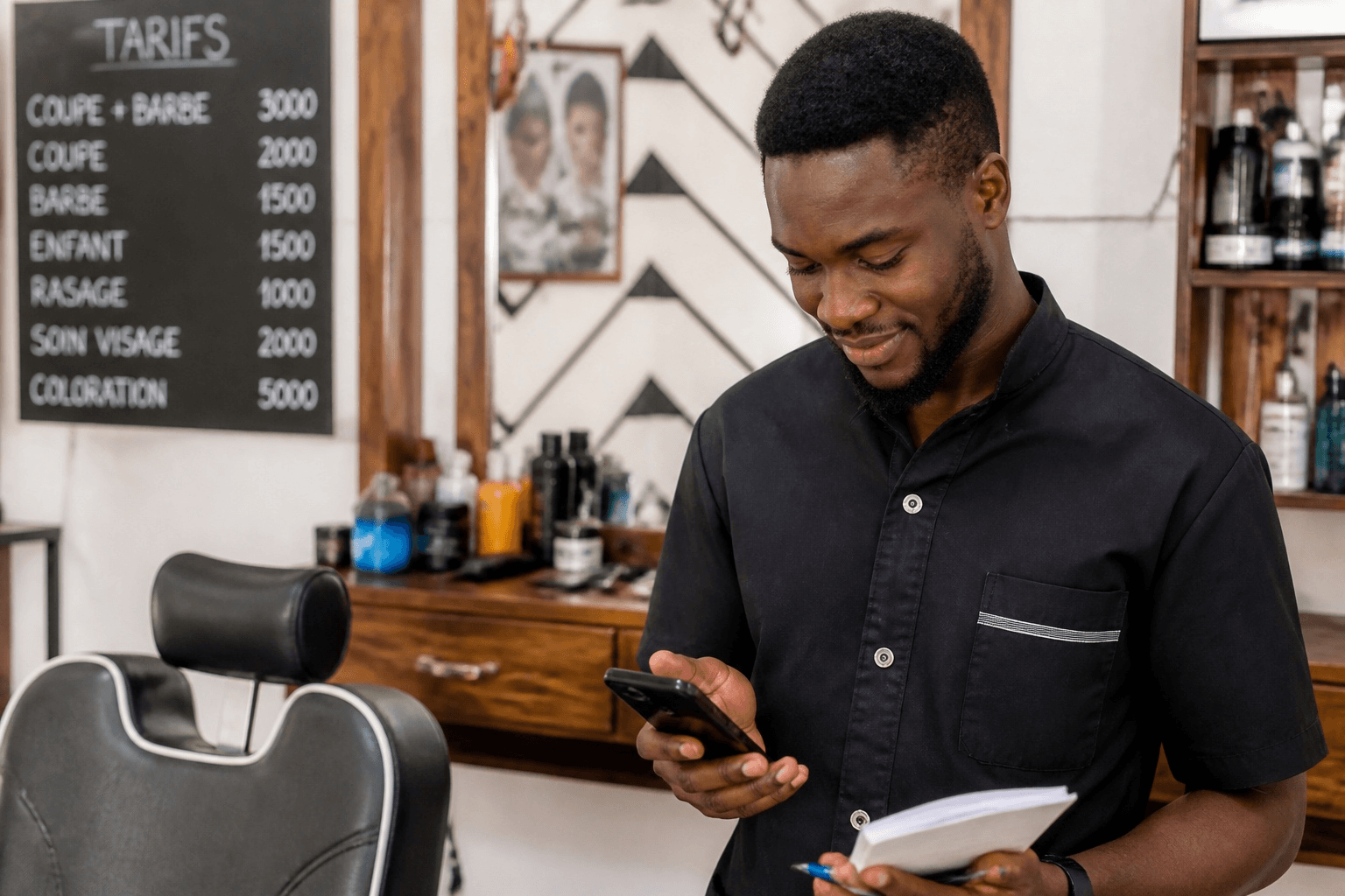 Coiffeur consultant son téléphone dans son salon, devant la liste des tarifs affichée au mur